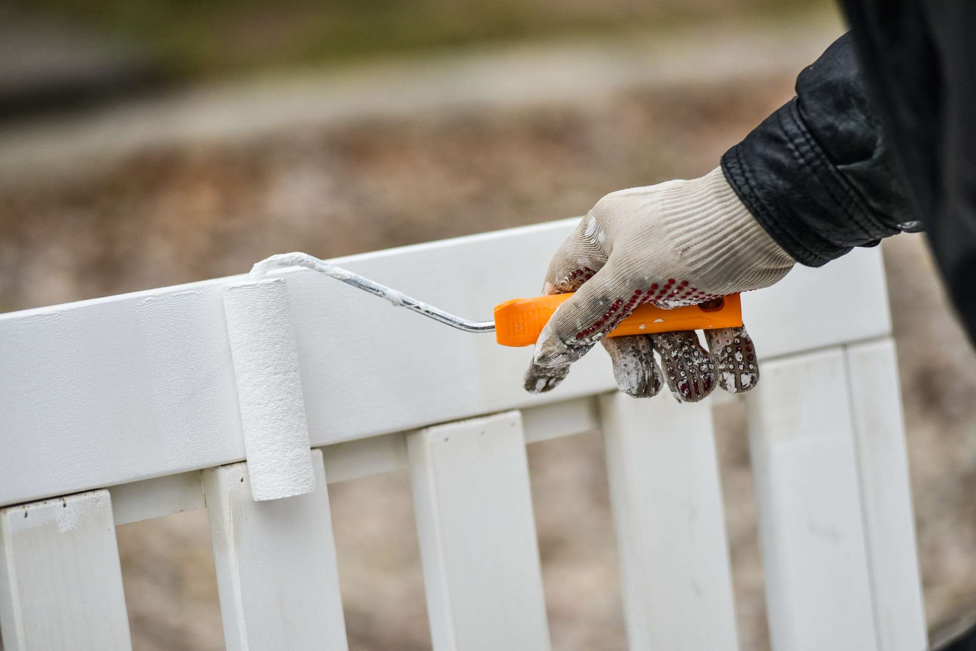 Man paints garden furniture white with a paint roller