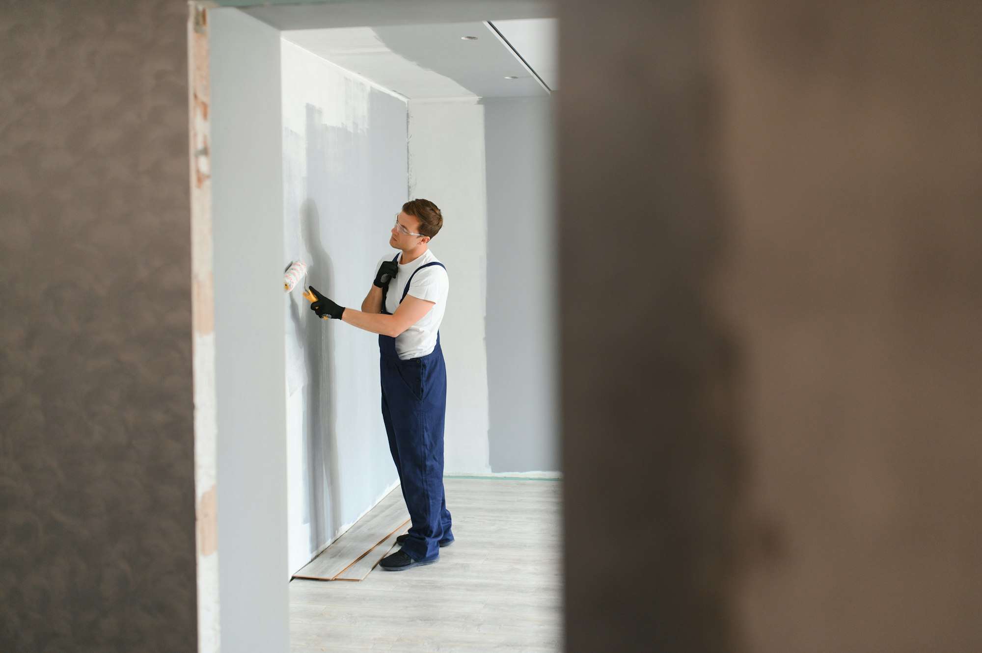 Worker painter paints a wall. Professional builder makes repairs.